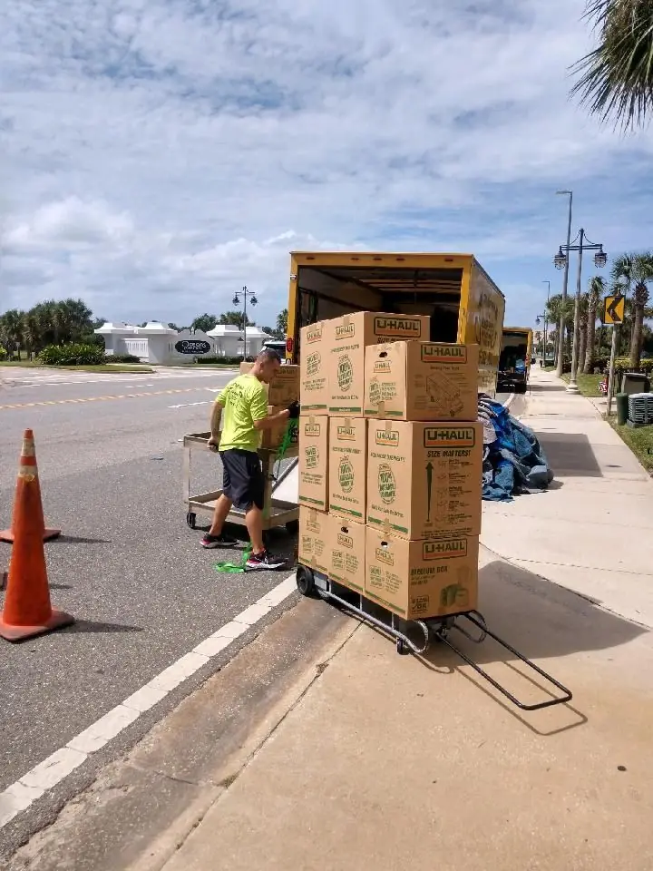 Mover wheeling a stack of packed boxes on a dolly
